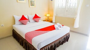 A neatly made bed with white and red bedding, a bedside lamp, and a window with white curtains. - OYO 1785 Villa Jeruk Ciwidey (Ciwidey)
