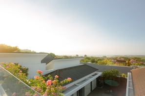Eine Dachterrasse mit Blick auf die Stadtlandschaft, ein Ziegeldach und einige Grünflächen.