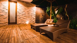 A wooden deck with wicker furniture and a green umbrella. - The Chandara Villa Bali (Nusa Dua)