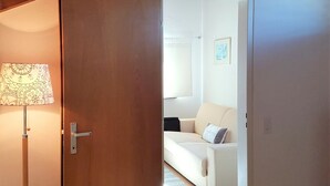A room with a wooden door, a lamp, and a white sofa. - Home near Franklin College and Lugano Center (Collina d'Oro)