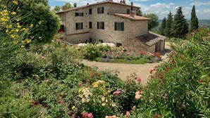 A stone building with multiple windows and a garden with various flowers. - Luxury Chianti in La Farfalla (Greve in Chianti)