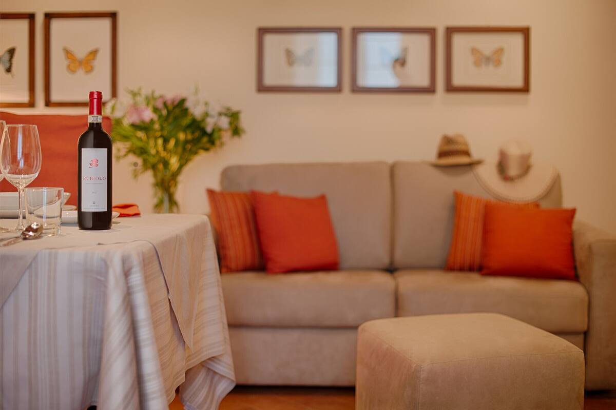 Une table à manger avec une bouteille de vin, des verres et un vase de fleurs.