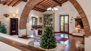An interior with a wooden ceiling, a fireplace, a bookshelf, and a staircase. - Luxury Privacy in the Heart of Tuscany (Pienza)