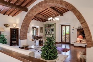 An interior with a wooden ceiling, a fireplace, a bookshelf, and a staircase. - Luxury Privacy in the Heart of Tuscany (Pienza)
