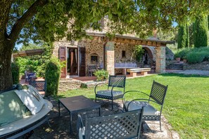 A stone building with a patio, outdoor seating, and a pergola.