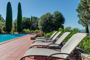 A poolside area with lounge chairs, a tiled deck, and a view of the pool. - Luxury Privacy in the Heart of Tuscany (Pienza)
