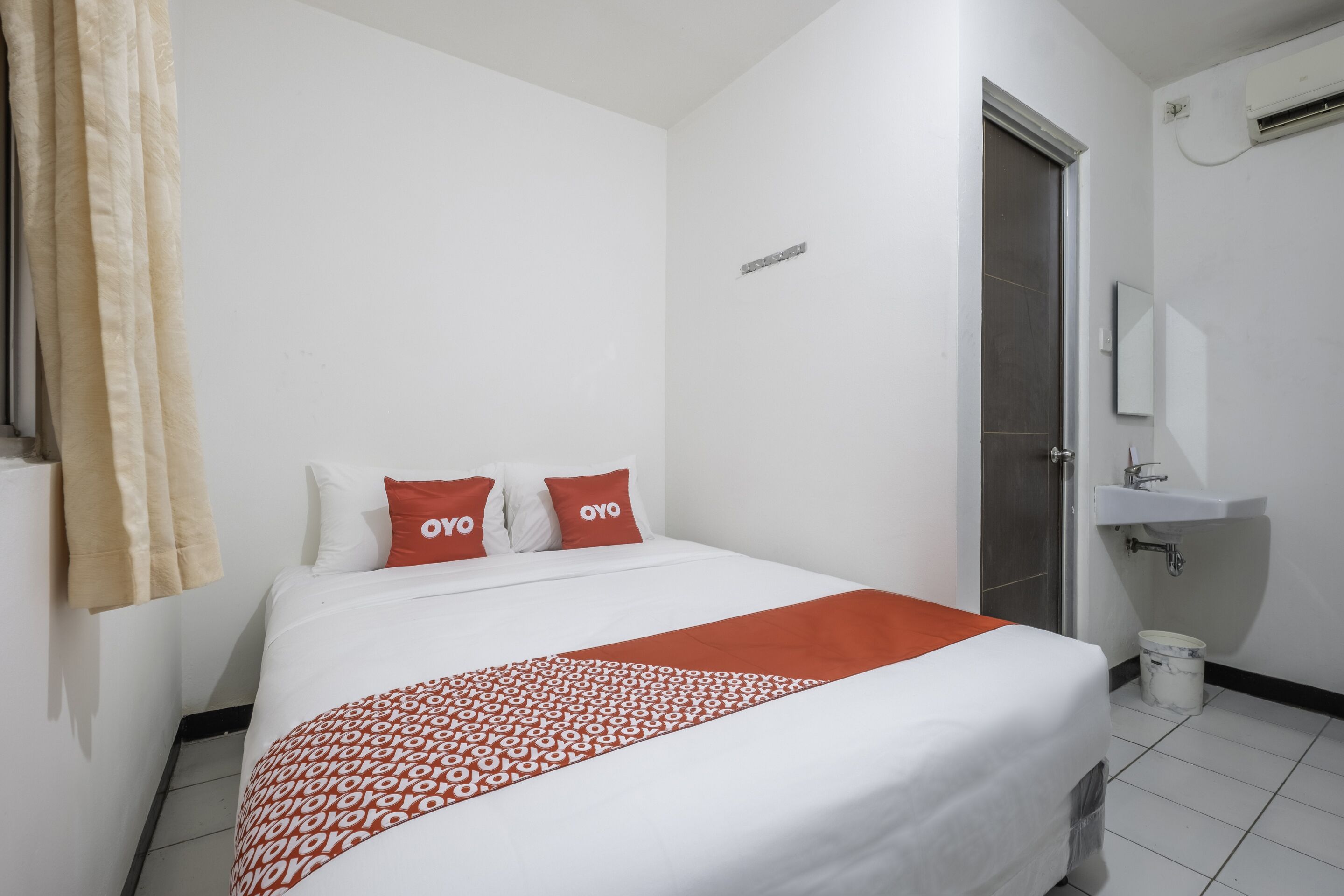 A hotel room with a bed, a bathroom with a sink, and a shower.