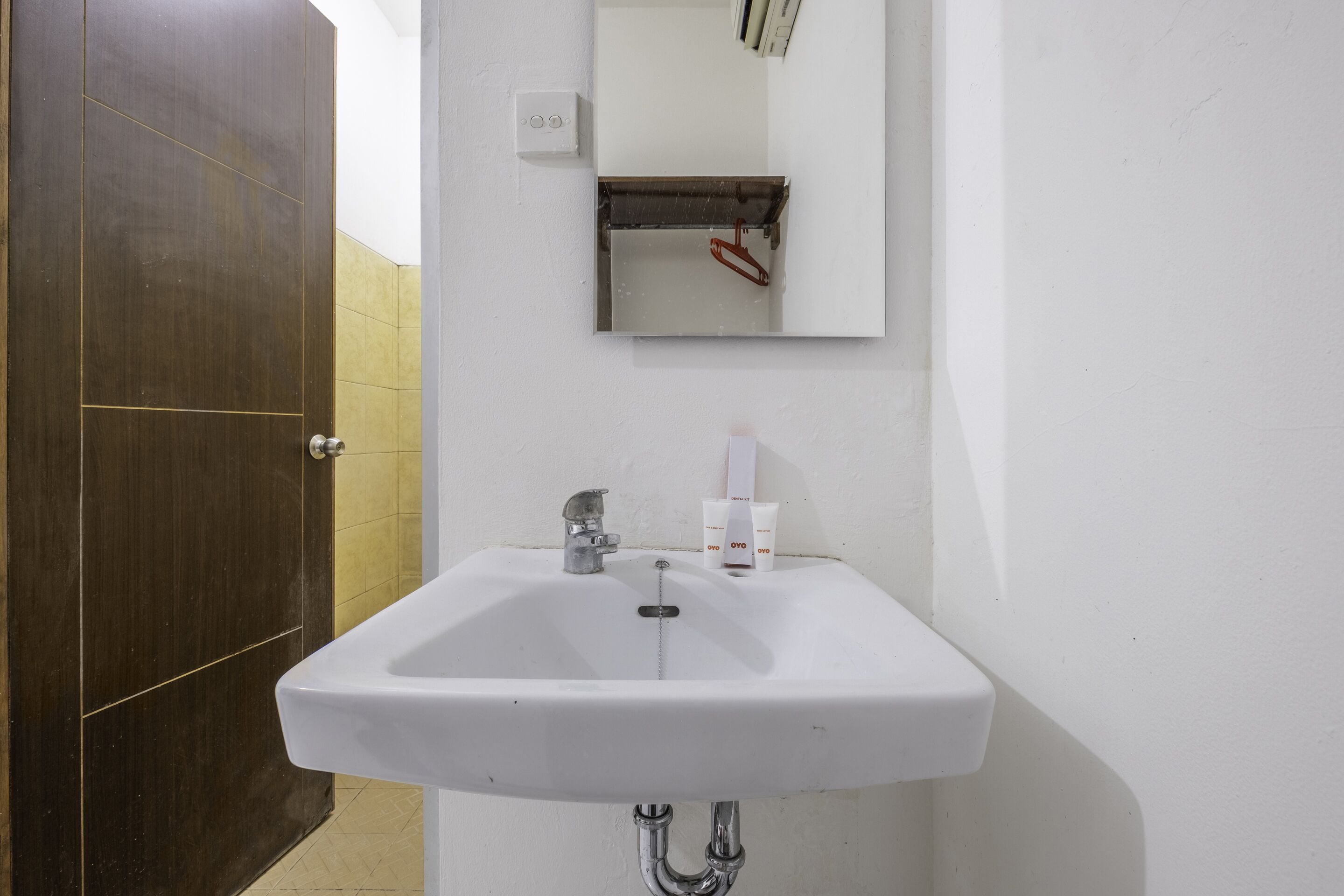 A bathroom with a white sink, a mirror, and a dark wooden door.