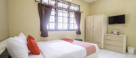 A bedroom with a bed, a wardrobe, a television, and a window with curtains.