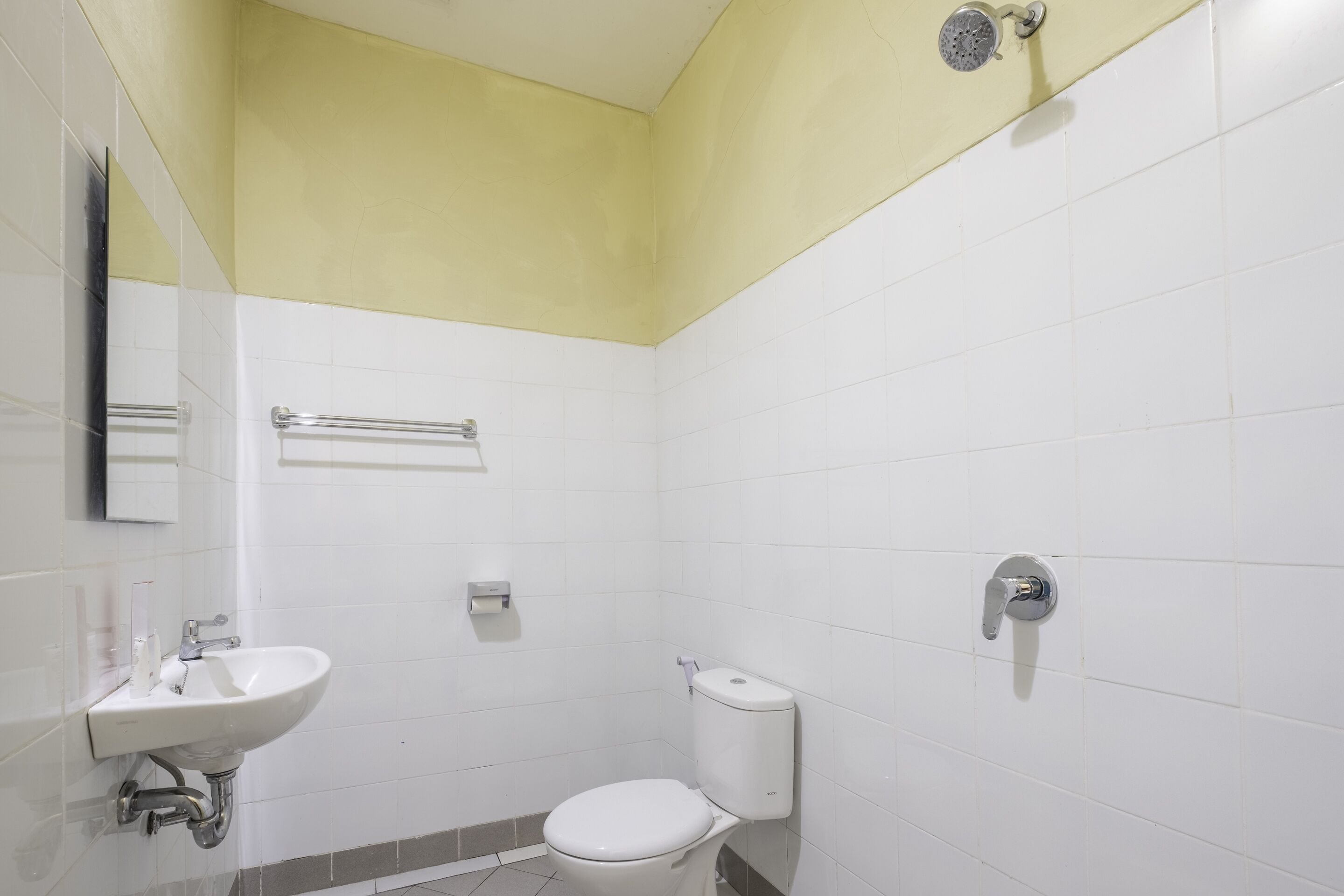 Un baño pequeño y limpio con lavamanos, inodoro y ducha blancos.