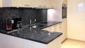 Una cocina moderna con encimeras de granito, electrodomésticos de acero inoxidable y armarios de madera clara.