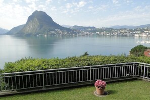 A view of a lake with a mountain in the background and a balcony with a potted plant. - Lugano With Panorama (Lugano)