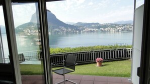 Un balcón con una silla, una planta en maceta y vistas a un lago y montañas.