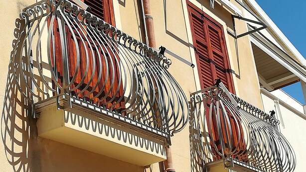 A building with two balconies featuring ornate wrought iron railings and red shutters. - near the sea and the center of San Vito Lo Capo is ideal for families (San Vito Lo Capo)