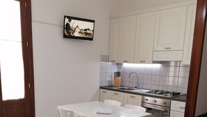 A kitchen with white cabinets, a tiled backsplash, a gas stove, and a dining table with chairs. - near the sea and the center of San Vito Lo Capo is ideal for families (San Vito Lo Capo)