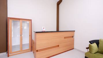 Una habitación con un mostrador de recepción de madera, una puerta corredera de vidrio y un sofá verde.