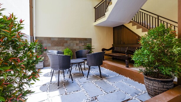 A modern outdoor patio with a stone floor, a dining table with chairs, and a staircase leading to an upper level.