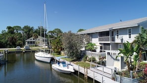 Ein Yachthafen mit einem vertäuten Segelboot, ein Haus mit einem Balkon und eine Anlegestelle, die ins Wasser hineinreicht.