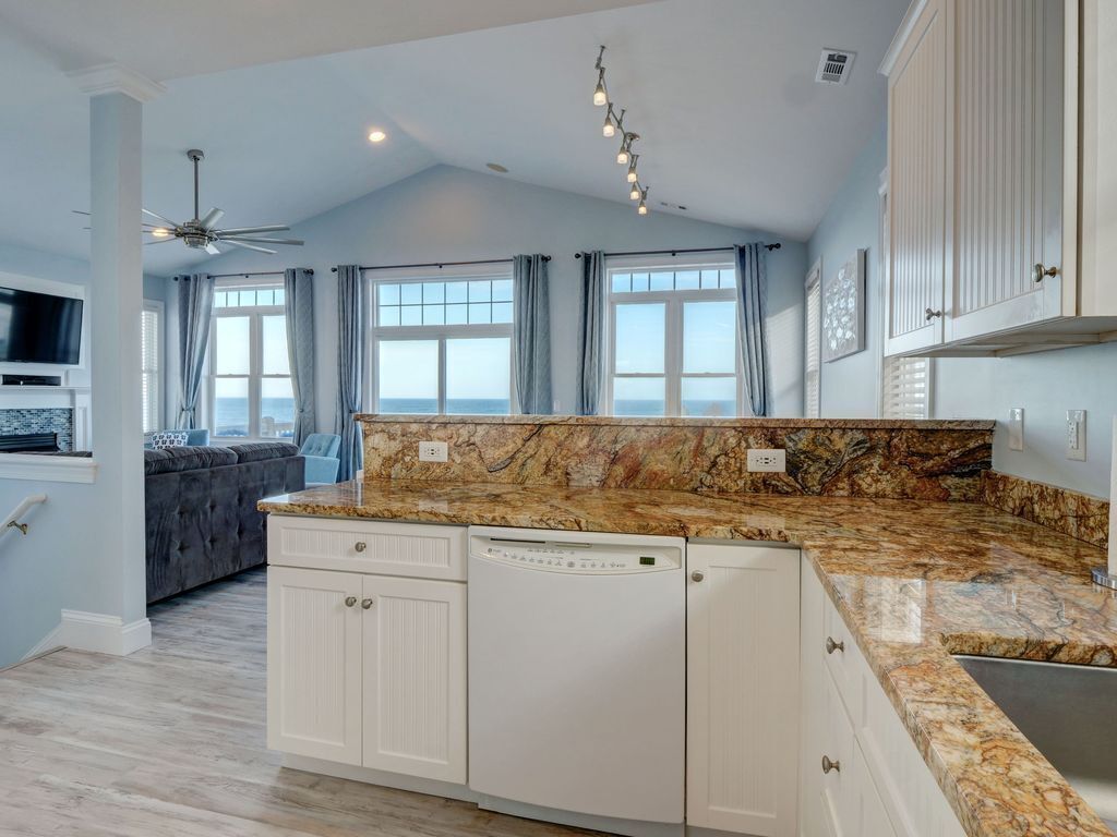A modern kitchen with granite countertops, white cabinetry, and a built-in dishwasher.