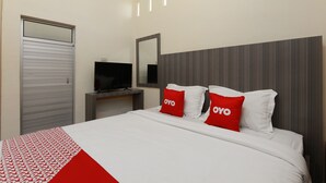 Una camera d'albergo con un letto, una televisione su un mobile, un armadio e uno specchio appeso al muro.