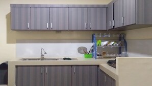 Una cucina con mobili grigi, un lavello e un piano di lavoro con scolapiatti e utensili.