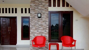 Una casa moderna con rivestimento in piastrelle, una porta in legno e due sedie rosse in plastica.