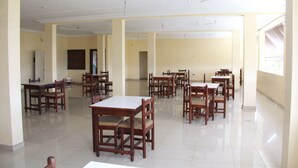 A spacious dining area with multiple wooden tables and chairs, high ceilings, and large windows allowing natural light. - Hotel Residence du Bonheur (Abidjan)
