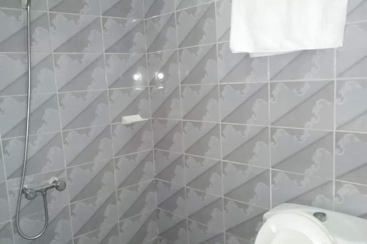 A bathroom with a shower, toilet, and a towel hanging on the wall.