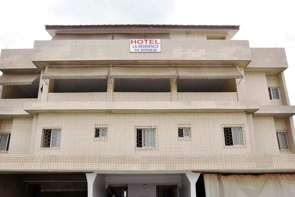 A multi-story building with a sign indicating it is a hotel named "Hotel La Residence Du Bonheur."