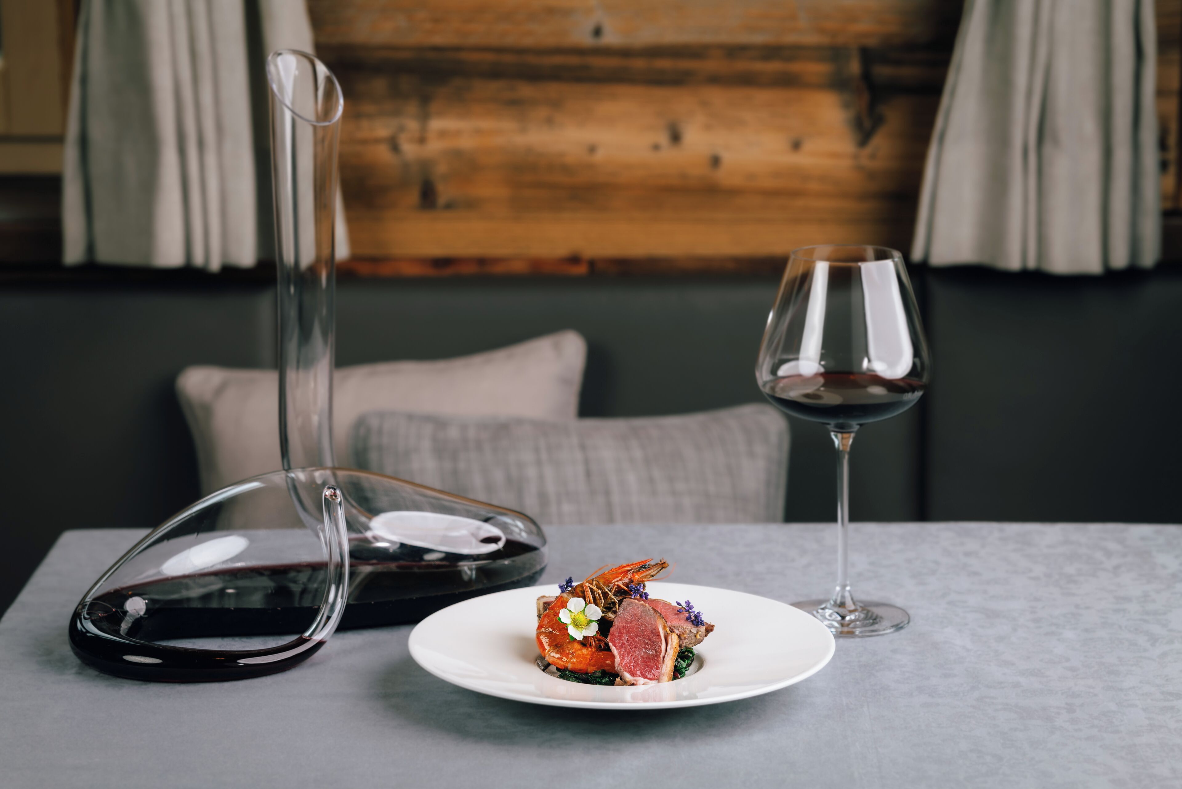 Una mesa de comedor con un plato de comida, una copa de vino y una botella de vino.