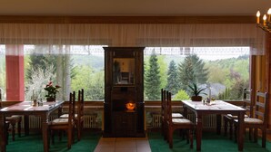 Un comedor con vista a un bosque, muebles de madera y una araña.
