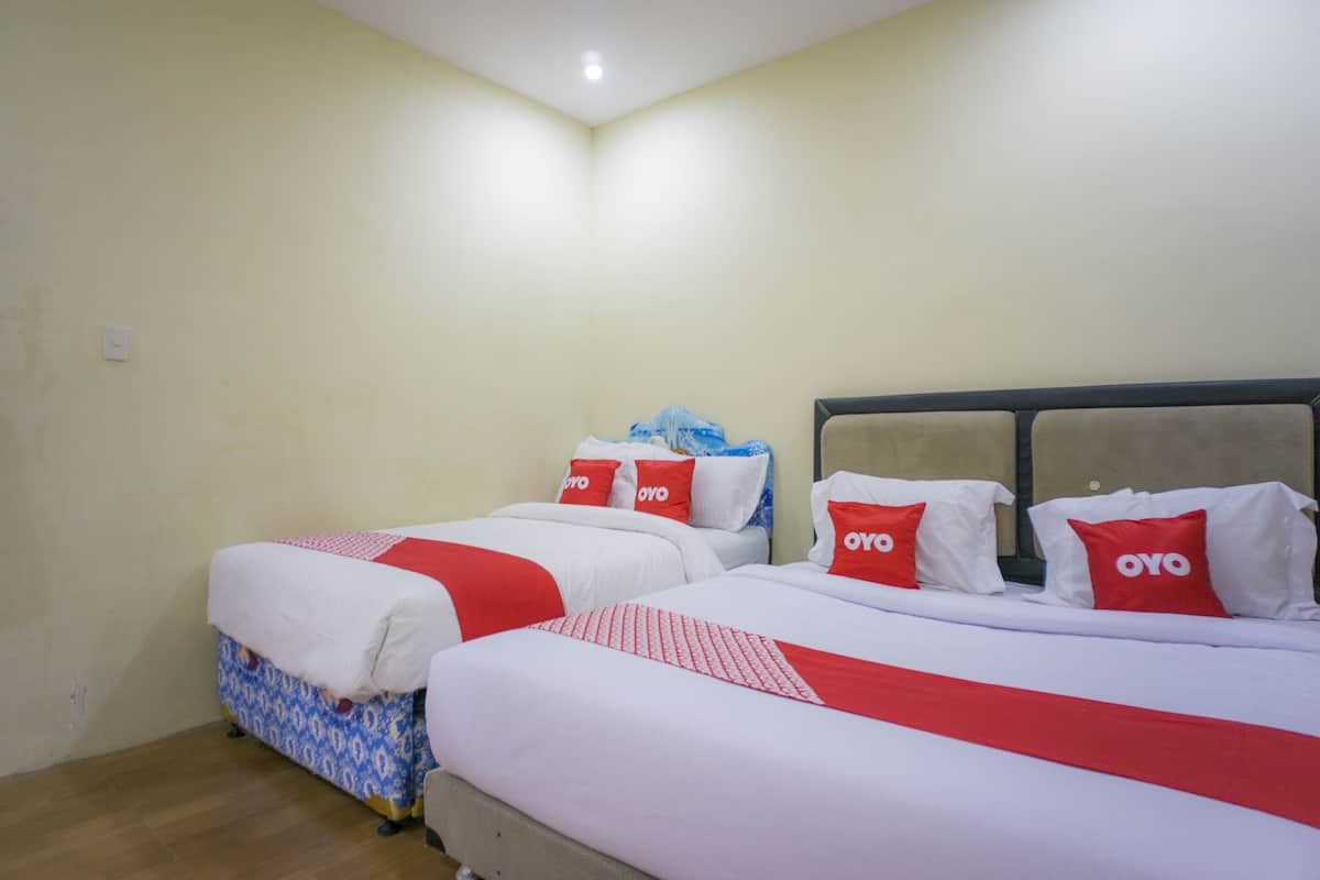 A hotel room with two beds, each with red and white bedding and pillows labeled "OYO".