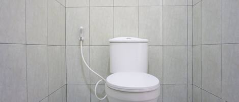 A bathroom with a toilet, tiled walls, and a geometric patterned floor.