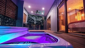 A modern indoor pool area with a hot tub, wooden deck, and a view of the outdoors. - Tuckers Lane Boutique Accommodation (North Rothbury)