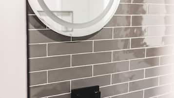 A bathroom with a modern design, featuring a round mirror and a stone sink.
