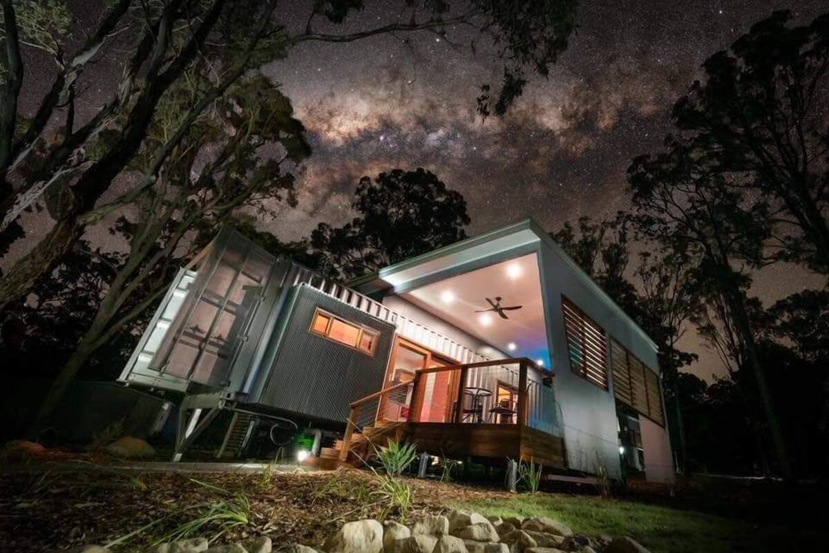 A modern house with a deck and a starry night sky visible through the windows.