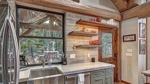 Una cocina moderna con un ventanal grande, electrodomésticos de acero inoxidable y detalles de madera.