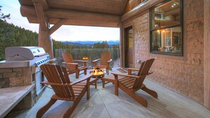 Un patio exterior con una parrilla, sillas de madera y un pozo de fuego.