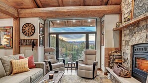 Una sala de estar acogedora con chimenea, dos sillones de cuero, una mesa de centro de madera y un amplio ventanal con vistas panorámicas.