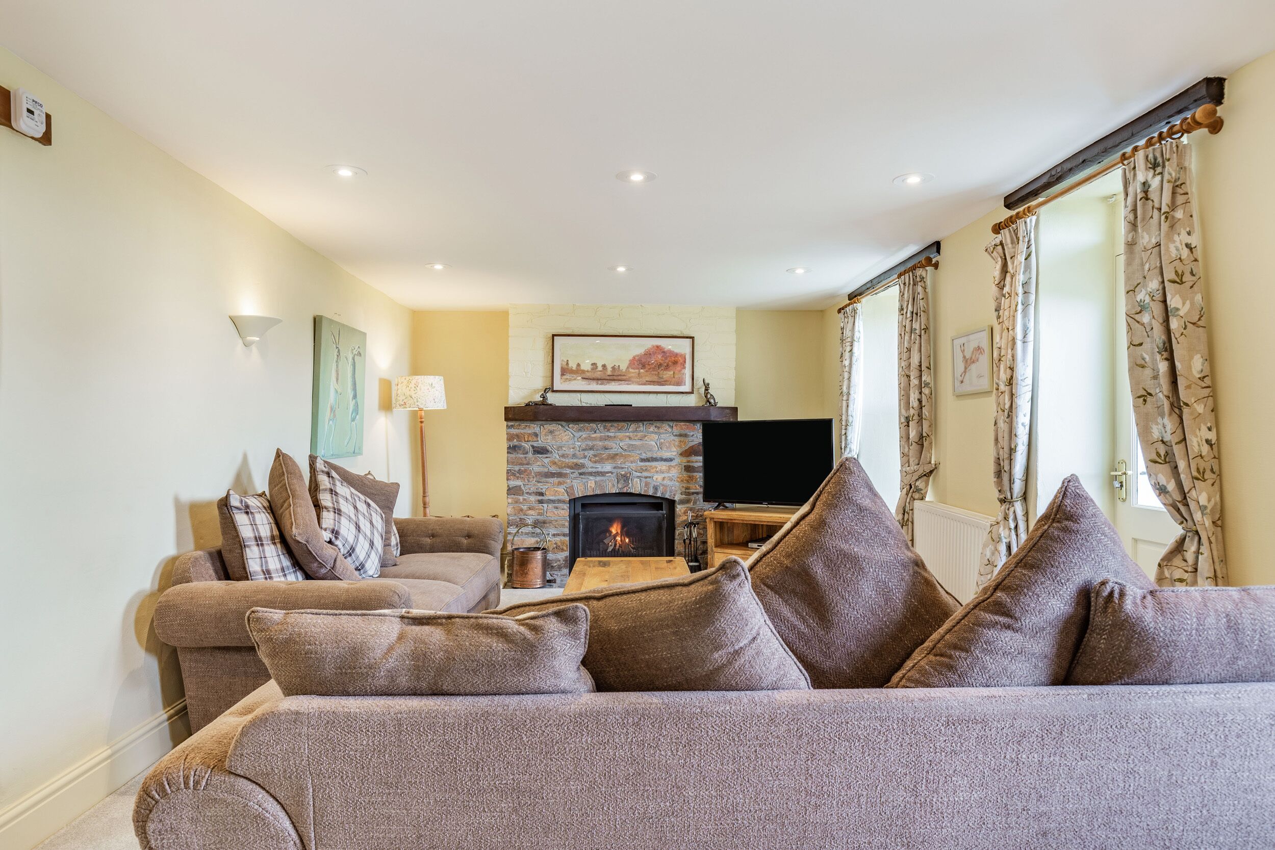 Una sala acogedora con chimenea, un conjunto de sofás y un televisor.