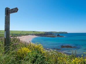 A coastal landscape with a wooden signpost indicating a public bridleway and a beach. - New Cottage (Kingsbridge)