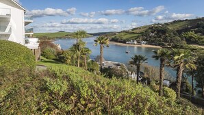 A coastal view with a white building, palm trees, and a river. - 2 Hamstone Court (Salcombe)