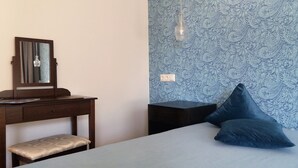 A bedroom with a bed, a bedside table, a dresser, a mirror, and a patterned wall. - Motel Zur goldenen Krone (Teterow)