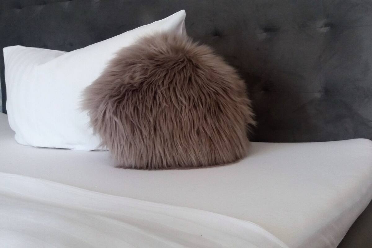 A bed with a fluffy pillow and a tufted headboard.