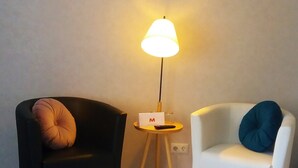 Two armchairs, one black and one white, with a small table and a lamp between them. - Motel Zur goldenen Krone (Teterow)