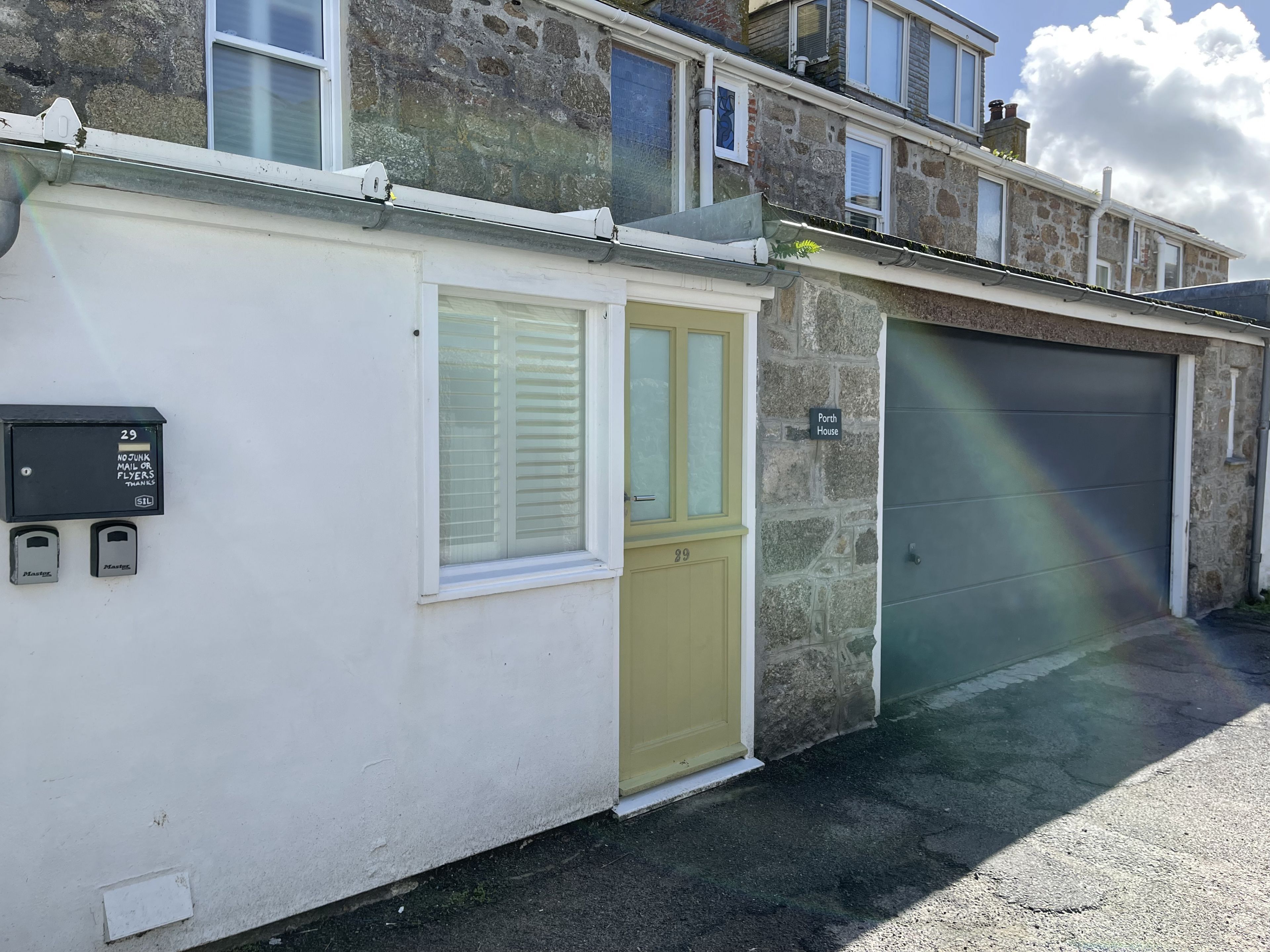 A residential building with a garage door, a mailbox, and a door with a window.