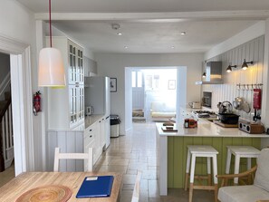 Une cuisine moderne avec des meubles blancs, un îlot central et un coin repas comprenant une table et des chaises.