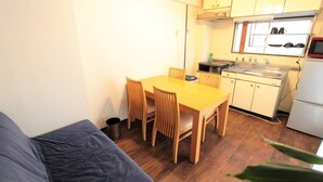 A compact kitchen with wooden cabinets, a dining table, and a built-in oven. - Okamura Mansion (Osaka)