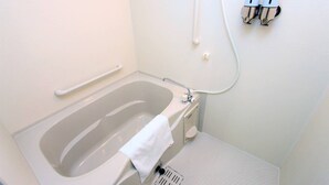 Une salle de bain équipée d’une baignoire, d’une barre d’appui, d’une serviette, d’un pommeau de douche et de deux distributeurs de savon.