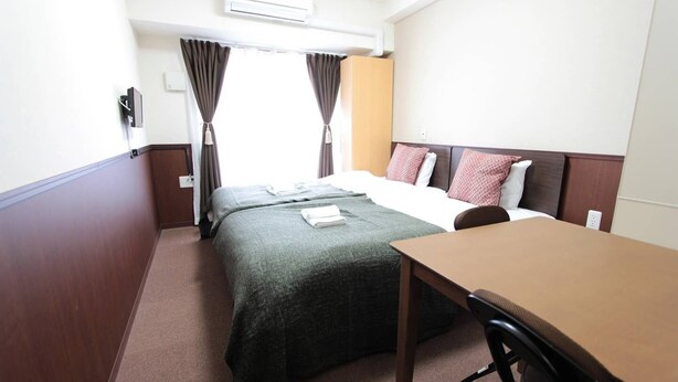 Une chambre d’hôtel avec deux lits, une table en bois et une chaise.